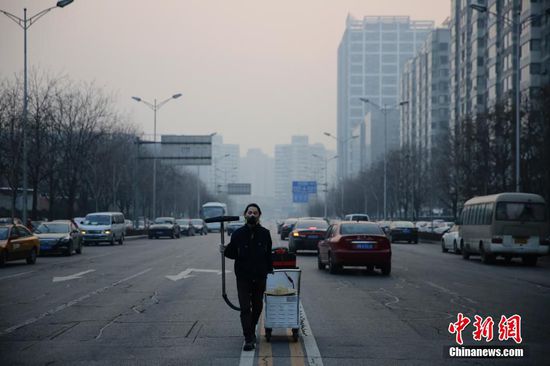2015年11月12日傍晚，北京，一位自称“坚果兄弟”的小伙，使用工业吸尘器为北京吸雾霾100天，他将用这100天内收集到的灰尘做一块板砖。图为北京吸霾第98天，坚果兄弟在望京SOHO建筑群周边作业。视觉中国